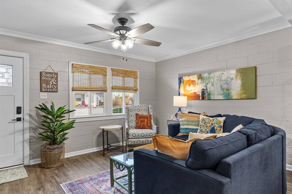 Unwind in your stylish living room with plush navy seating, warm wood floors, and a gentle ceiling fan overhead.