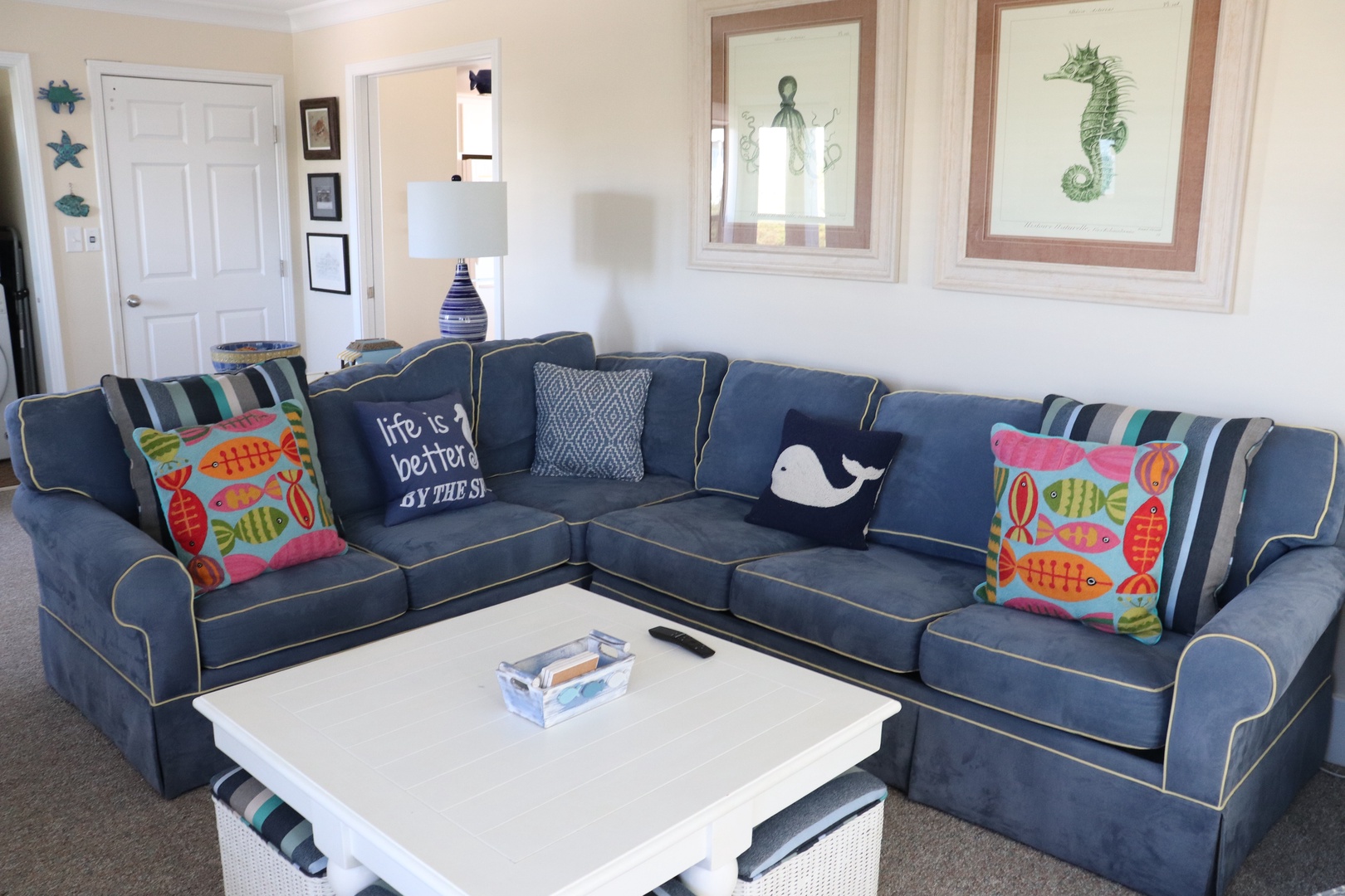 Sink into this spacious navy sectional adorned with colorful coastal pillows, where your vacation conversations flow naturally around the white coffee table.