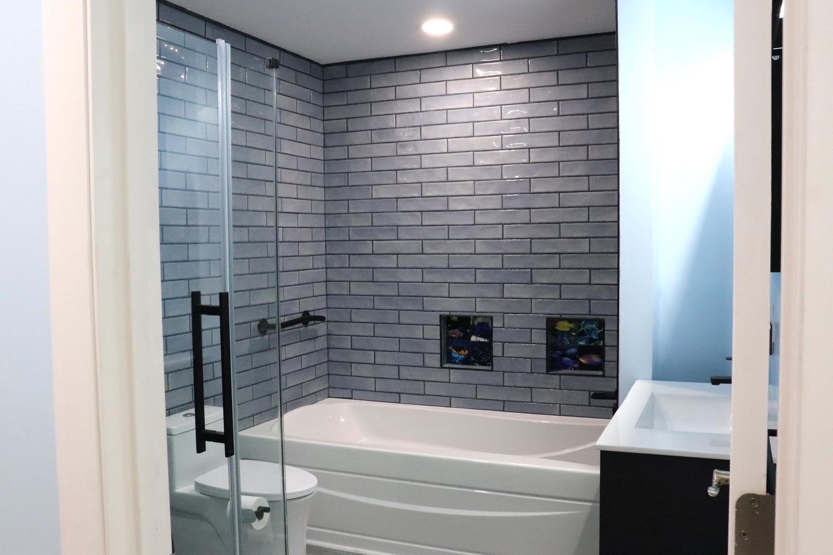Your private bathroom features chic gray subway tile, a soaking tub, and a sleek glass shower—perfect for unwinding after a day of adventure.