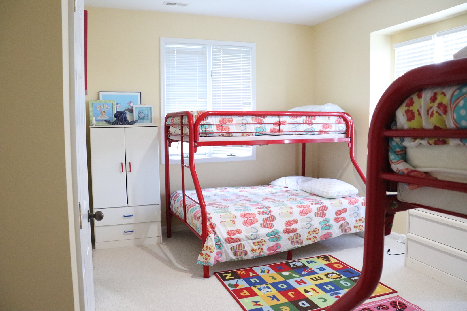 Your kids will love this cheerful room featuring bright red bunk beds and playful bedding, creating the perfect space for family adventures.