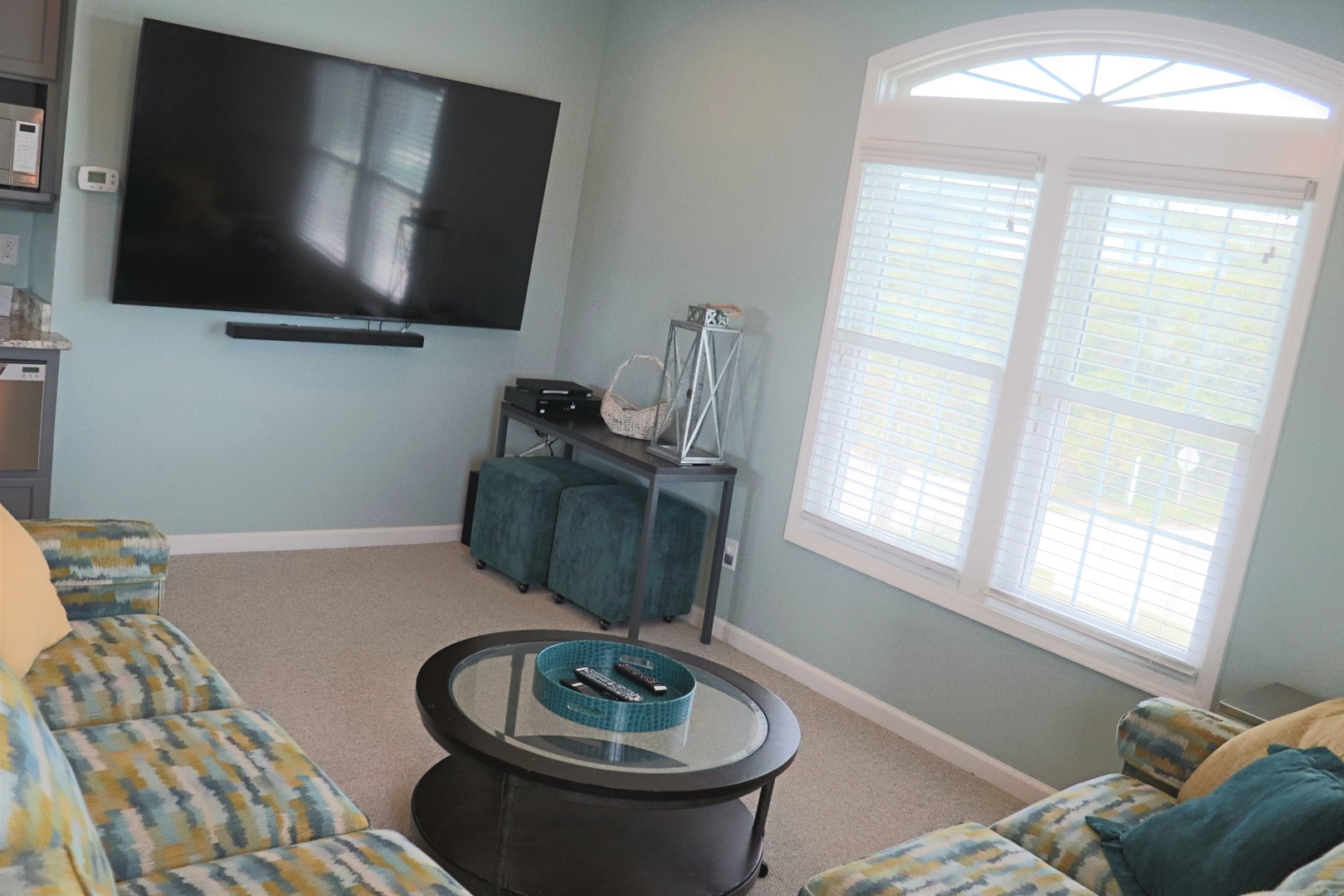 Relax in your bright living area with comfortable seating, large TV, and beautiful arched window flooding the space with natural light.