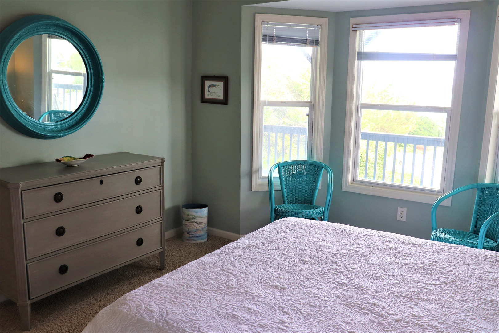 Relax in your bright, coastal-themed bedroom with turquoise accents and cheerful windows overlooking peaceful surroundings.