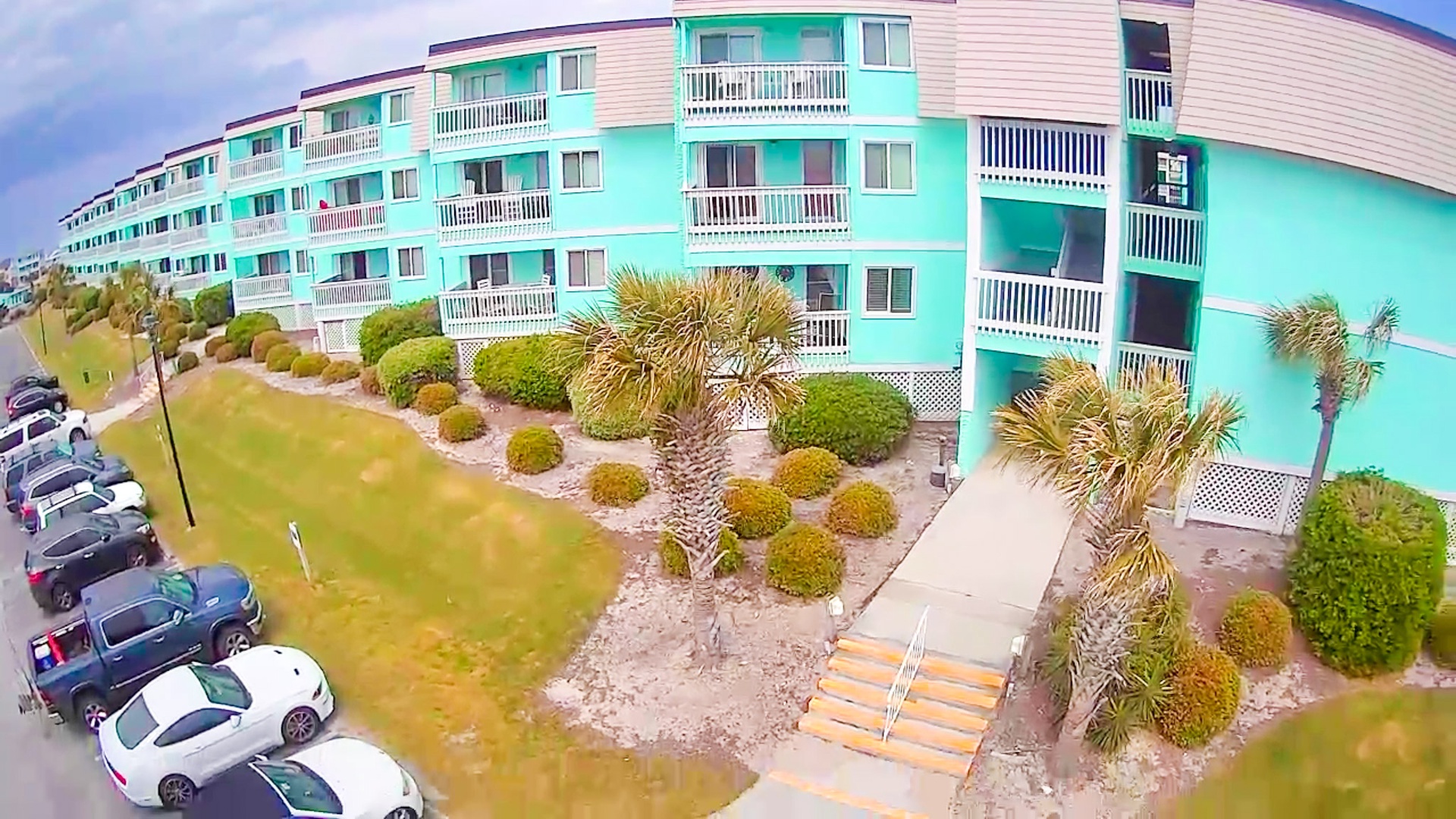 Colorful multi-story vacation rental building with tropical landscaping and convenient parking.