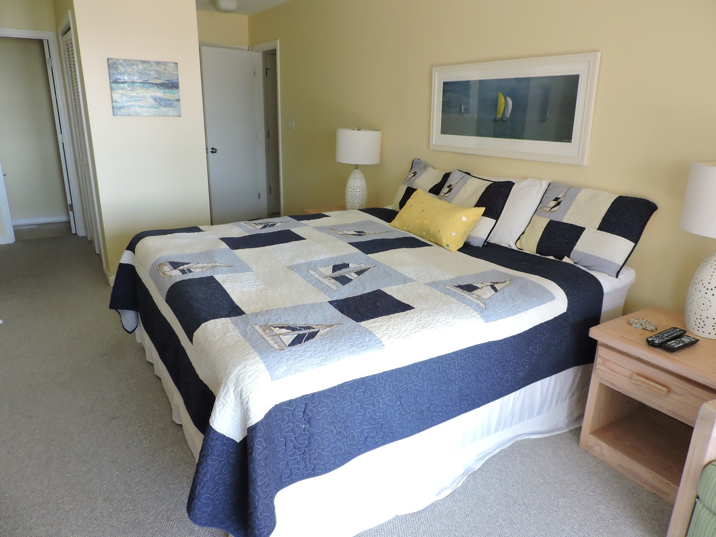 Unwind in your nautical-themed bedroom with cozy quilted bedding and cheerful sailboat art welcoming you to peaceful nights.