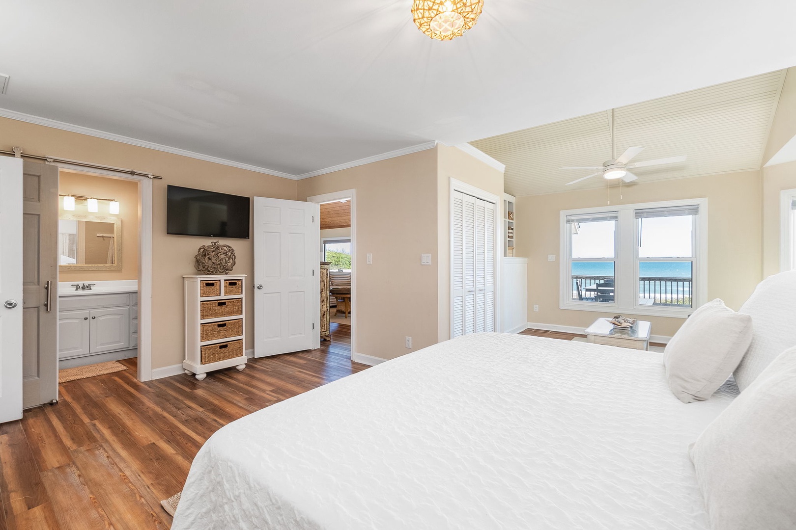 Wake up to stunning sea views from your comfortable bed in this bright, coastal bedroom with warm hardwood floors and elegant décor.