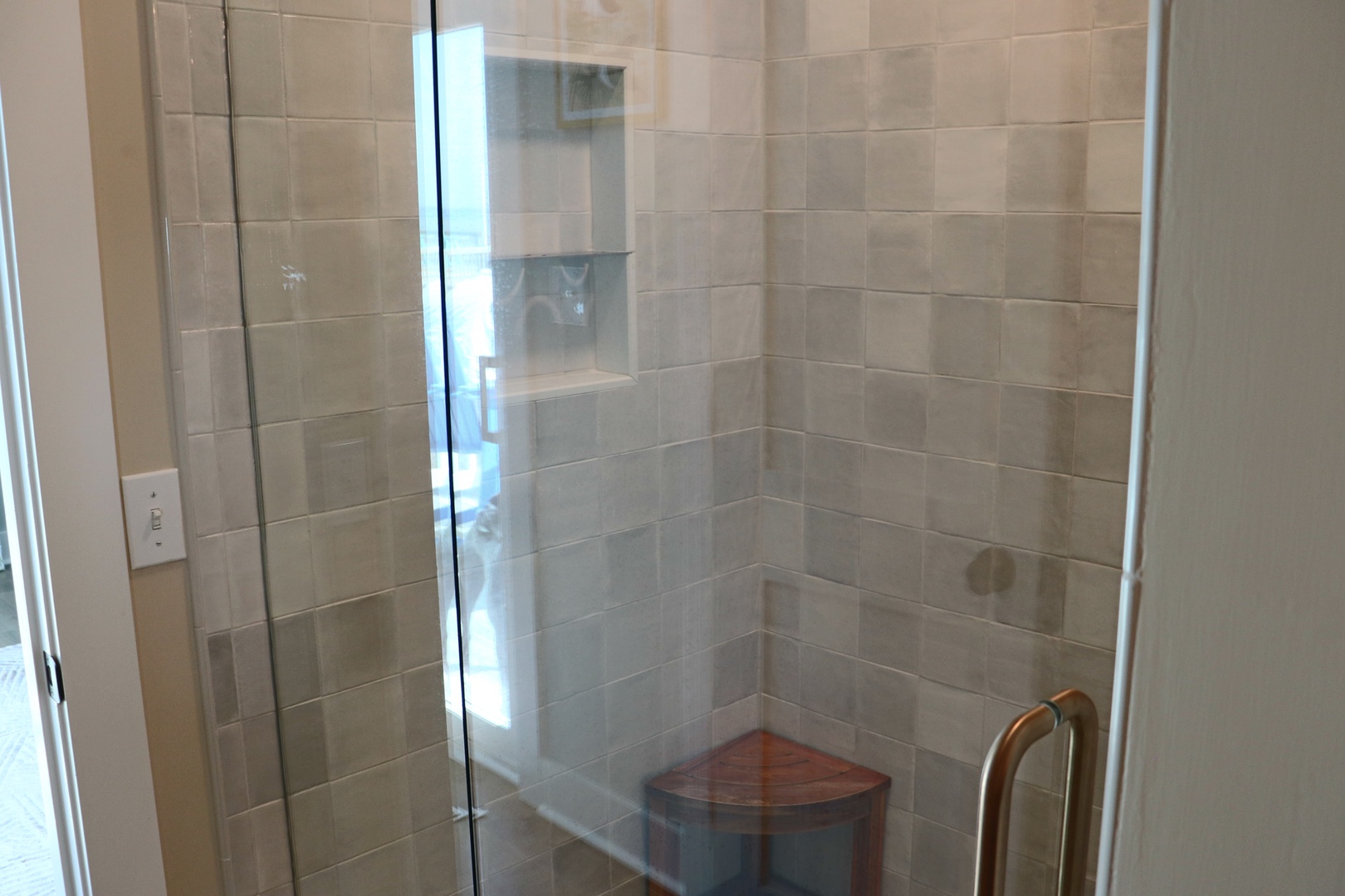 Step into your private shower sanctuary with elegant tile work and built-in corner seating for ultimate relaxation.