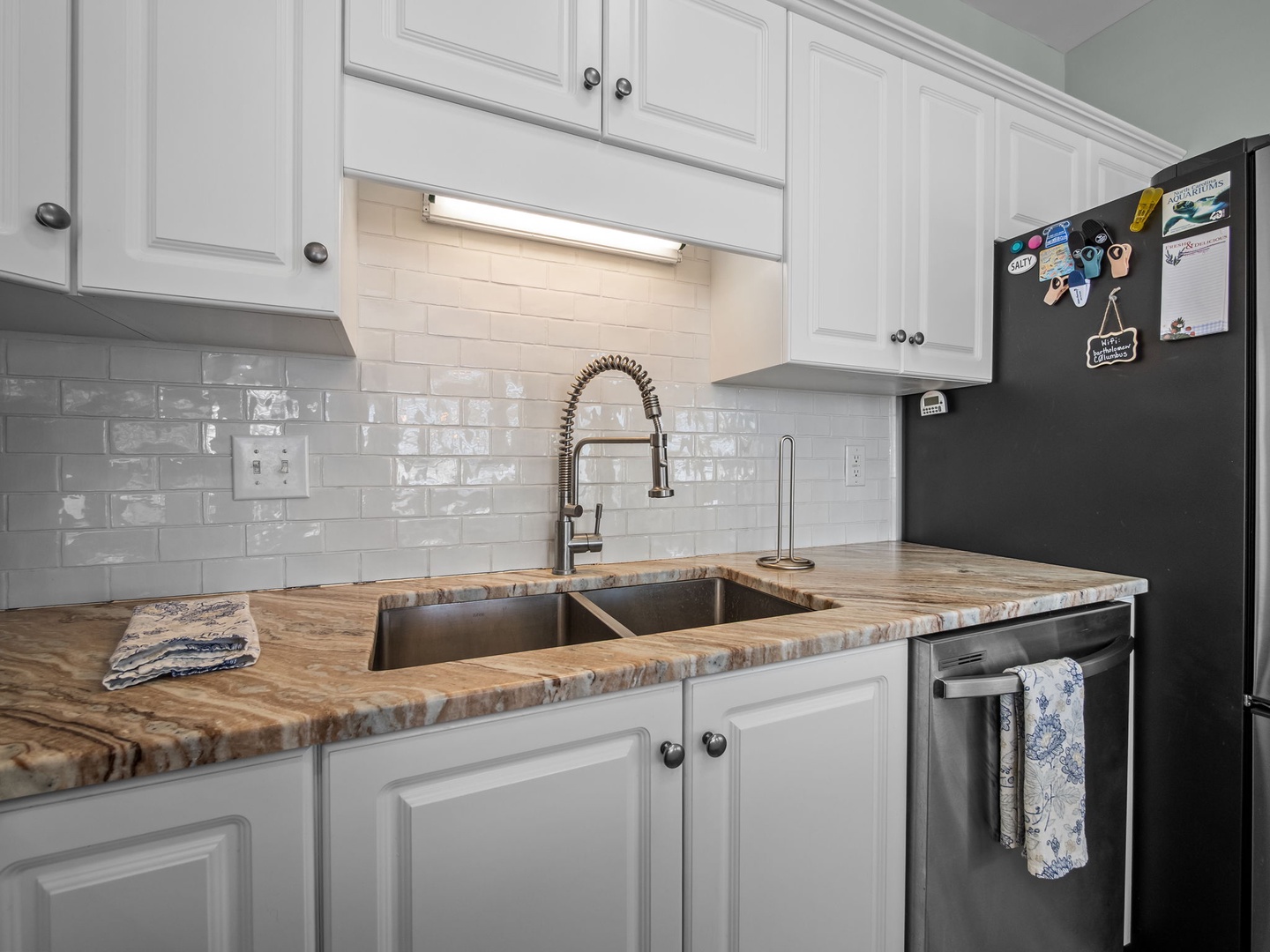 Your fully-equipped kitchen features gleaming granite counters, professional-grade faucet, and crisp white subway tile - perfect for preparing memorable meals during your stay.
