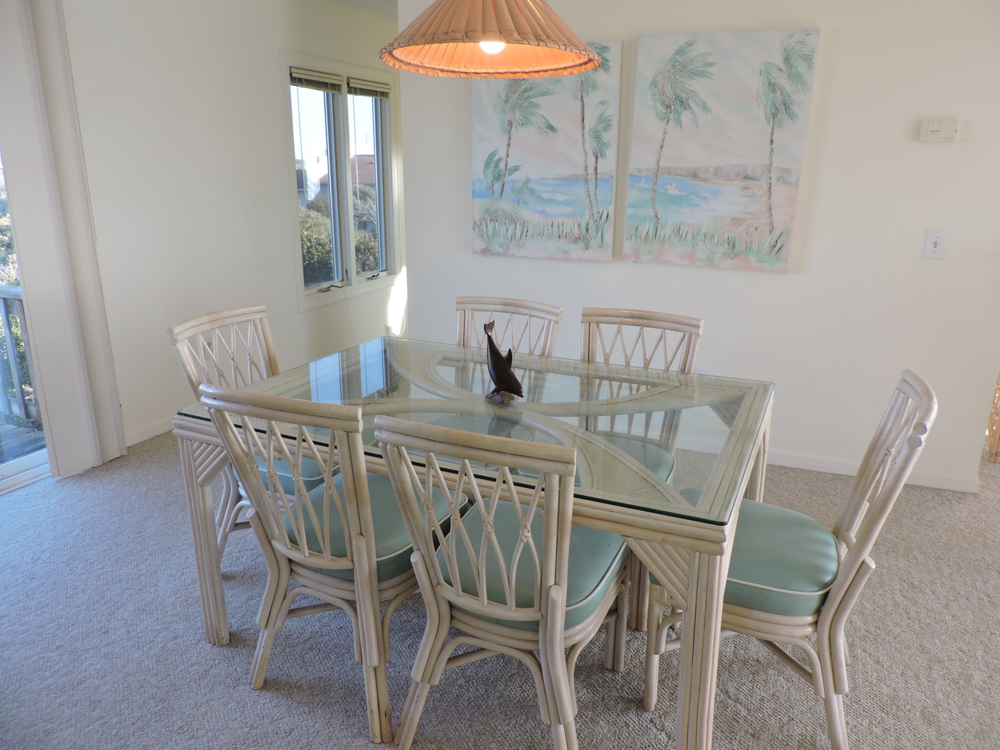 Gather around your bright dining space with tropical touches and natural light streaming through windows for memorable meals.