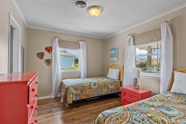 Wake up to stunning ocean views from your cozy twin bedroom with vibrant coral furniture and cheerful coastal touches.