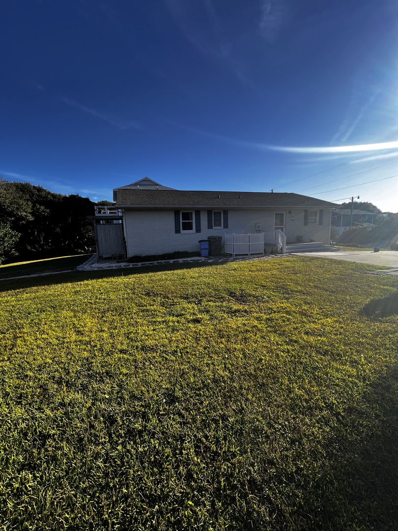 Modern property building surrounded by expansive green fields and natural landscape under clear blue skies.