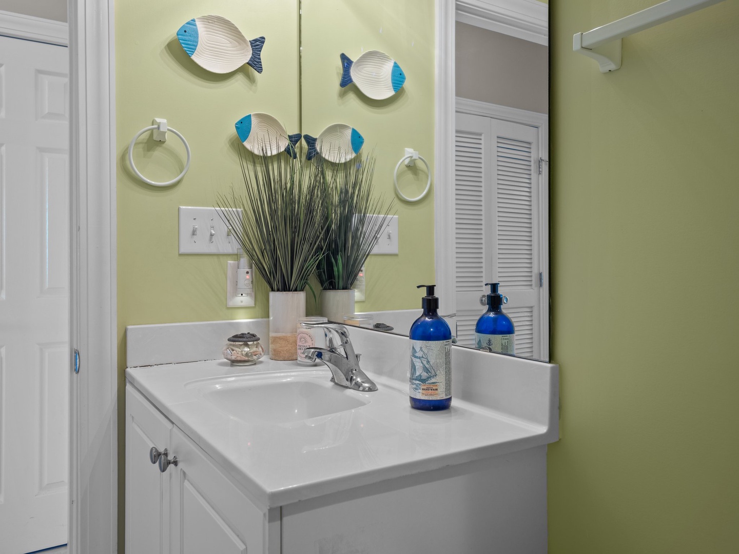 Fresh up in your bright coastal bathroom with tropical fish art and premium amenities awaiting your arrival.