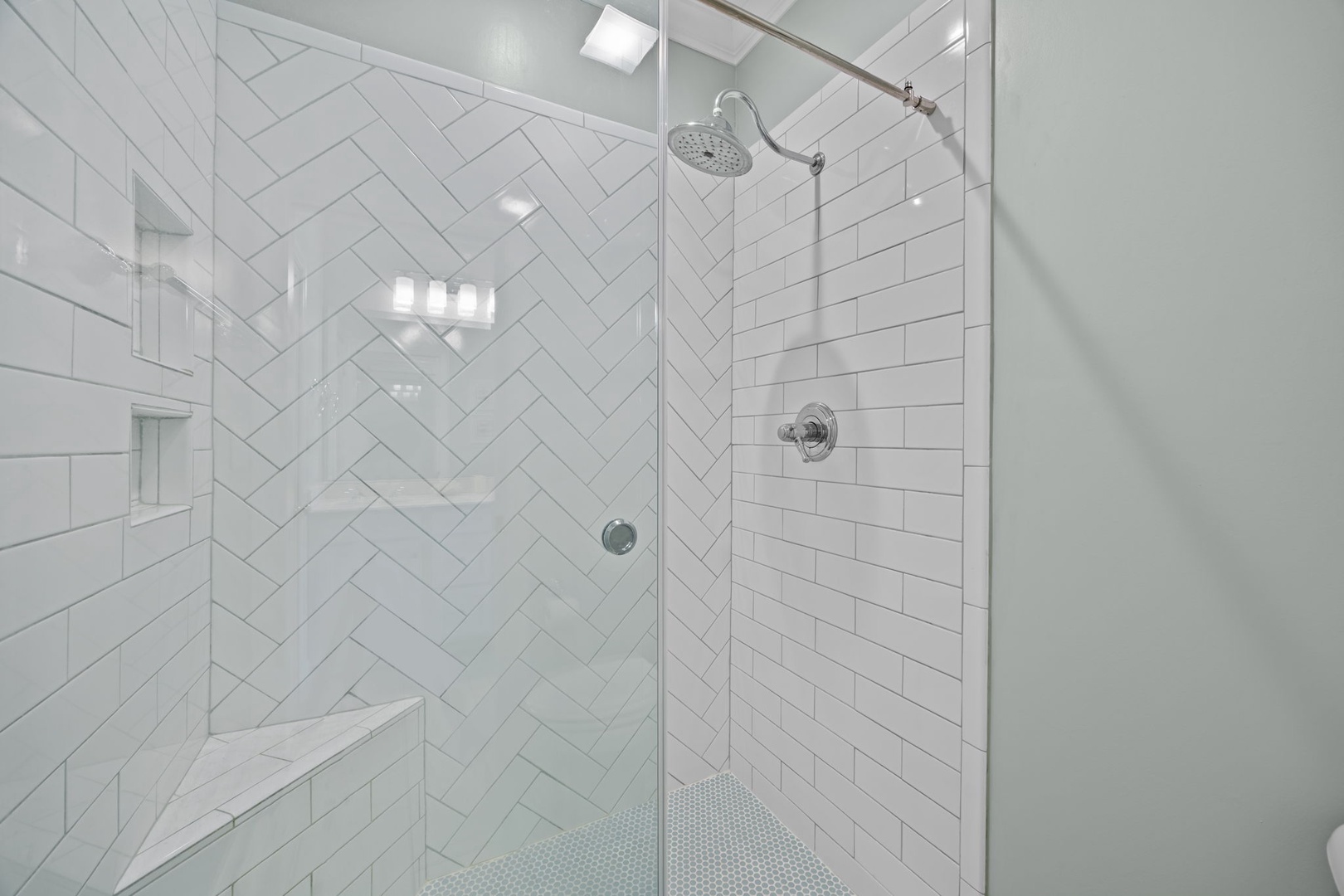 Rinse away stress in your stunning glass-enclosed shower featuring elegant herringbone tiles and rainfall head.