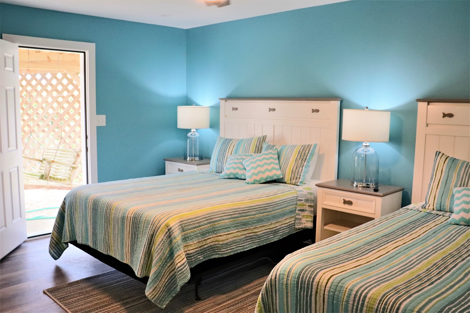 Rest peacefully in your coastal-inspired bedroom with twin beds, soothing turquoise walls, and private patio access for morning coffee or evening relaxation.