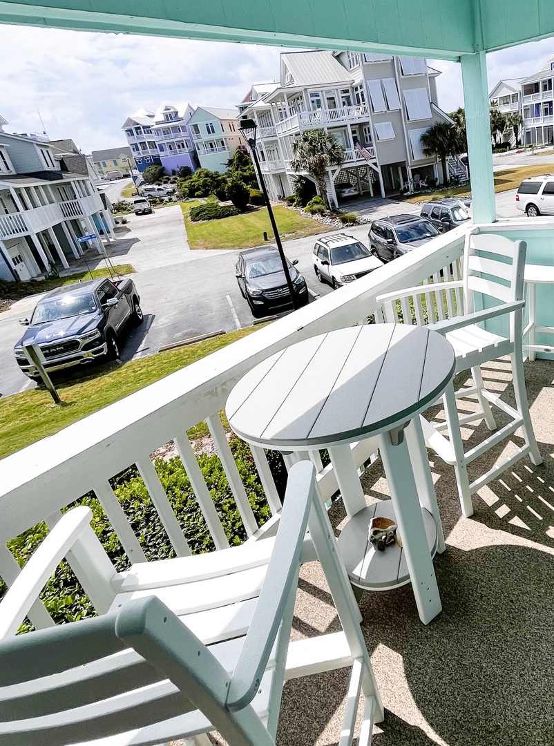 Sip your morning coffee at this cozy balcony table overlooking the charming coastal neighborhood below.