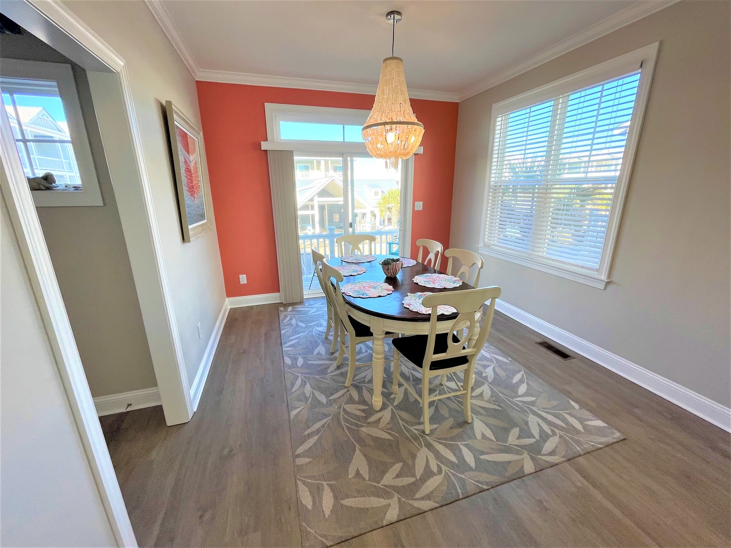Gather around your elegant dining table where warm coral accents and a stunning chandelier create the perfect setting for memorable meals.
