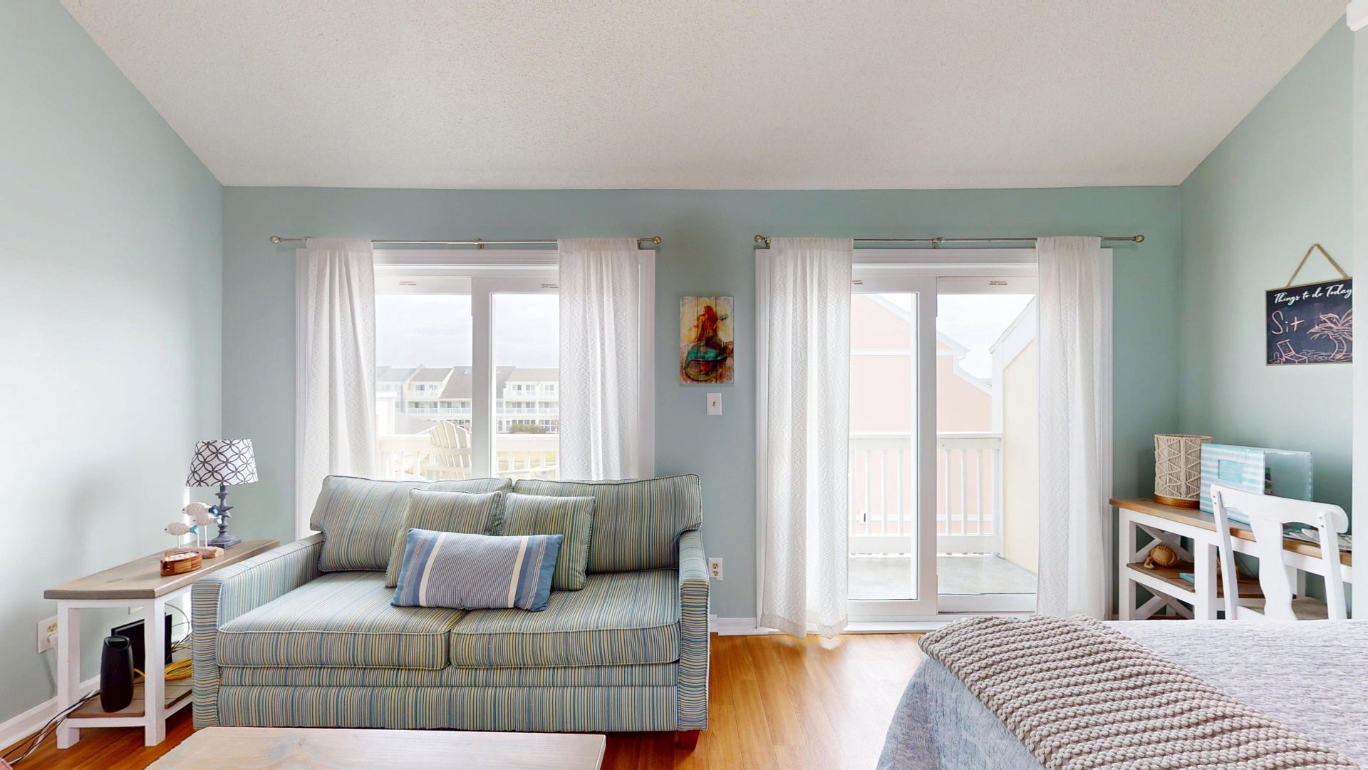 Relax in your airy bedroom with coastal decor, comfortable sofa, and French doors opening to your private balcony.