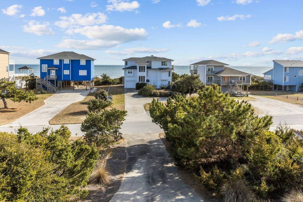 Coastal vacation homes nestled among natural dunes, just steps from the ocean with convenient parking and beach access.