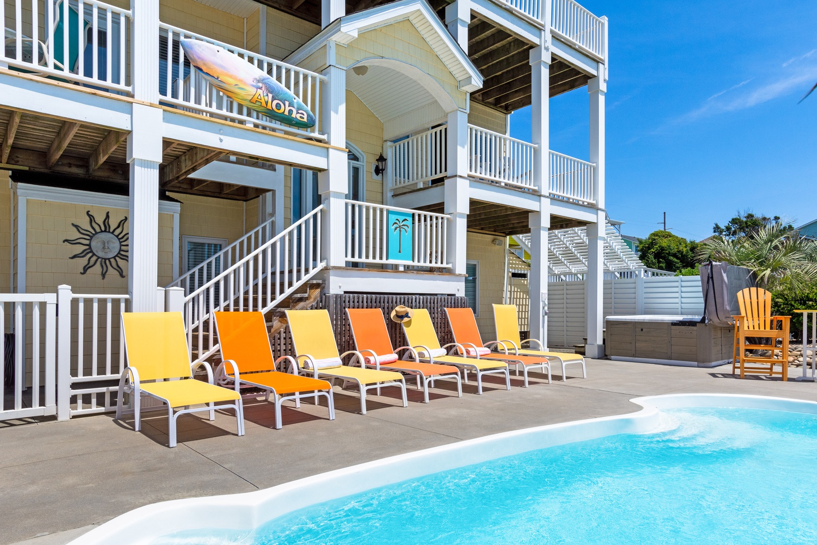Soak up the sun on colorful loungers beside your private pool, with the beautiful beach house creating the perfect tropical backdrop for relaxation.