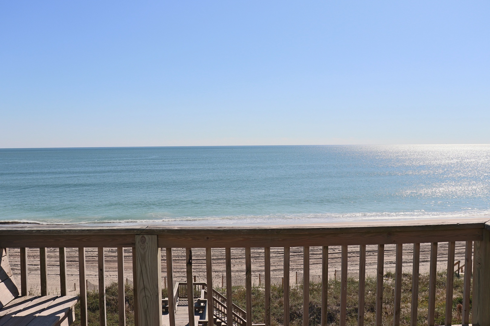 Pristine ocean views stretch endlessly beyond this beachfront deck, where gentle waves meet sugar-white sand in perfect serenity.