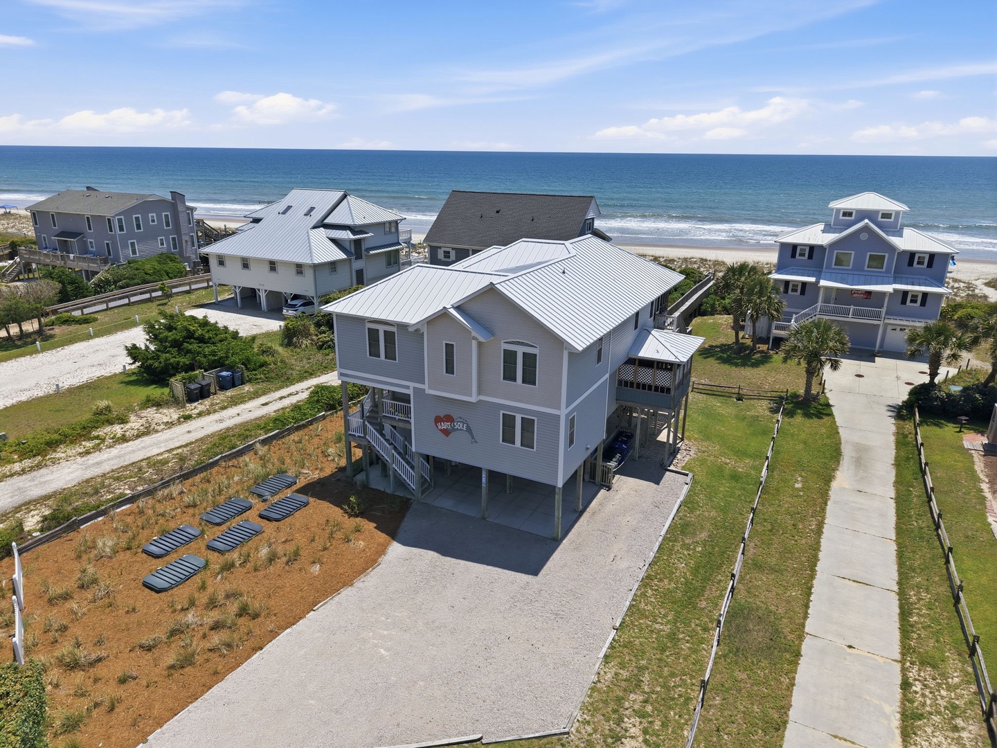 Elevated beachfront property with direct ocean access, modern coastal architecture, and spacious outdoor areas nestled among neighboring beach homes in a serene coastal community.