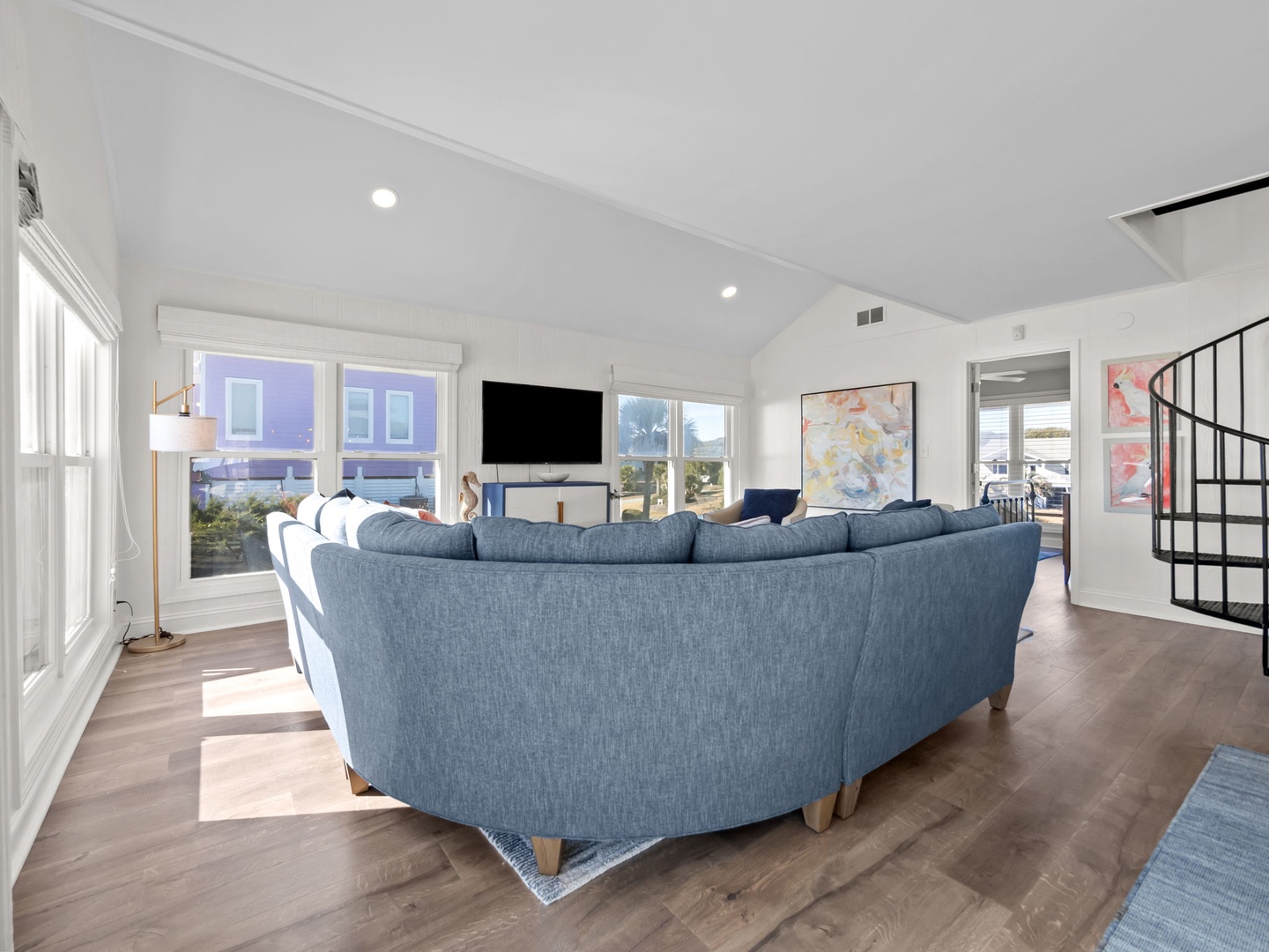 Sink into plush blue sectional seating while natural light floods your bright, airy living space with soaring vaulted ceilings and modern comfort.
