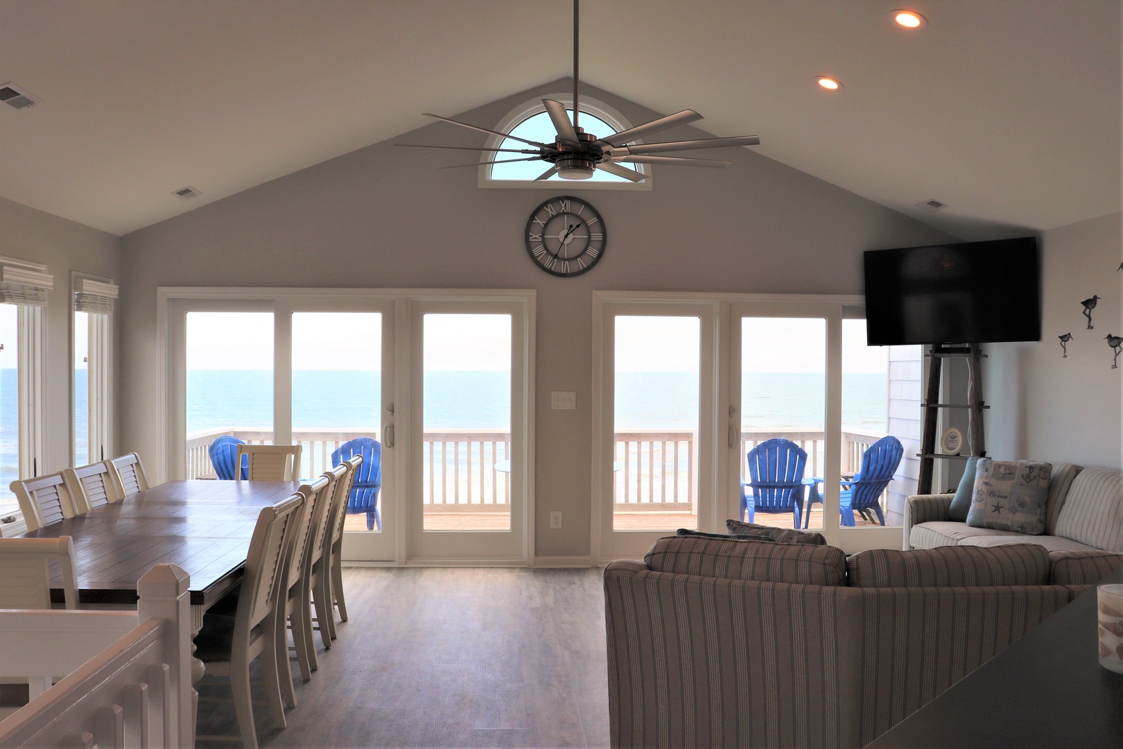 Relax in your airy living space with soaring ceilings and floor-to-ceiling windows revealing ocean views and deck access.