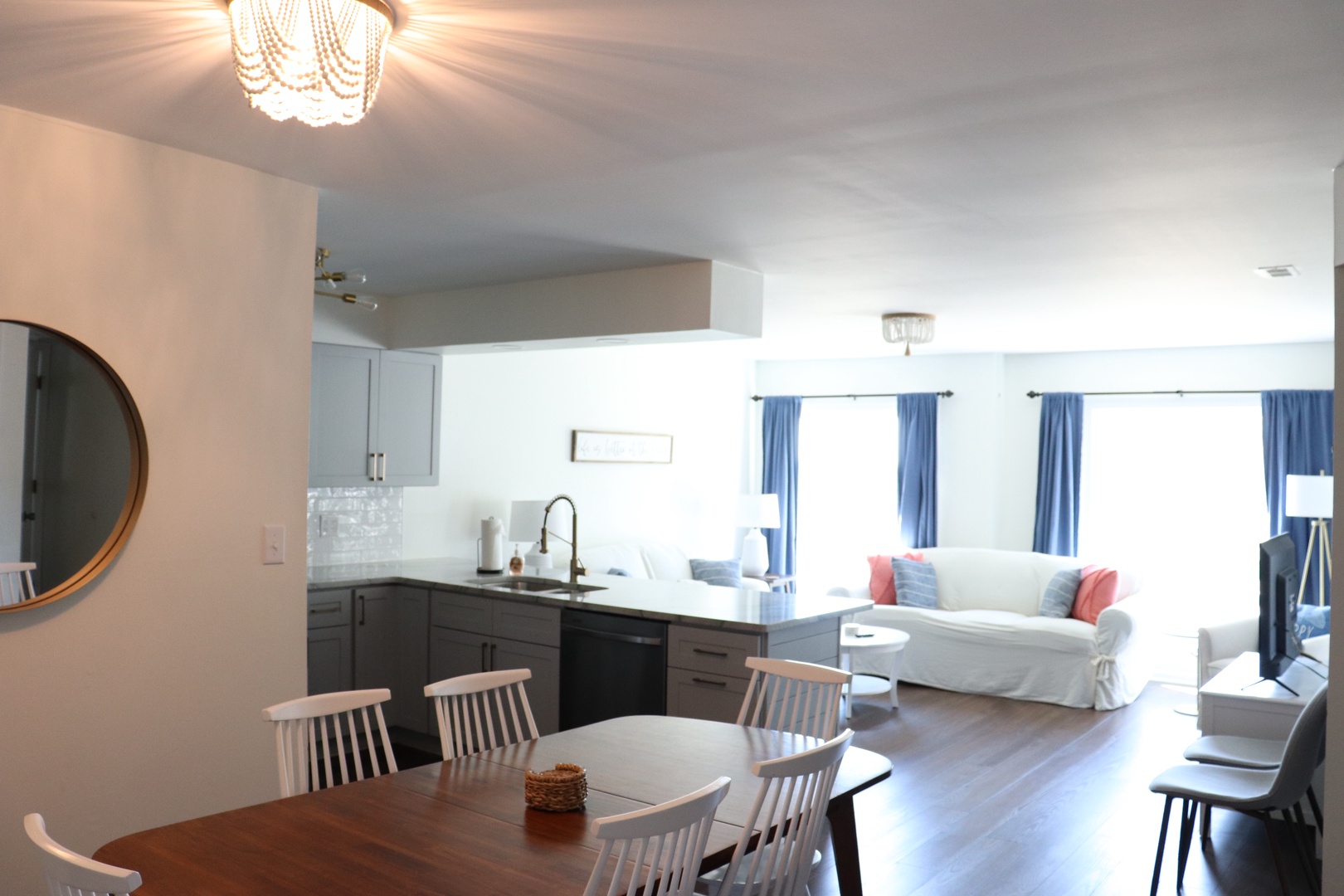 Gather around your spacious dining table while natural light streams through cheerful blue curtains, creating the perfect setting for memorable meals together.