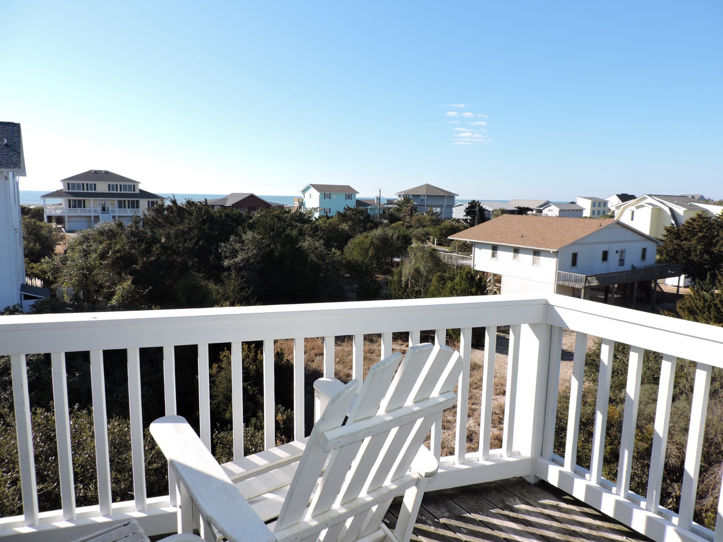 Relax in your private balcony chairs while enjoying peaceful views of the coastal neighborhood and clear blue skies.