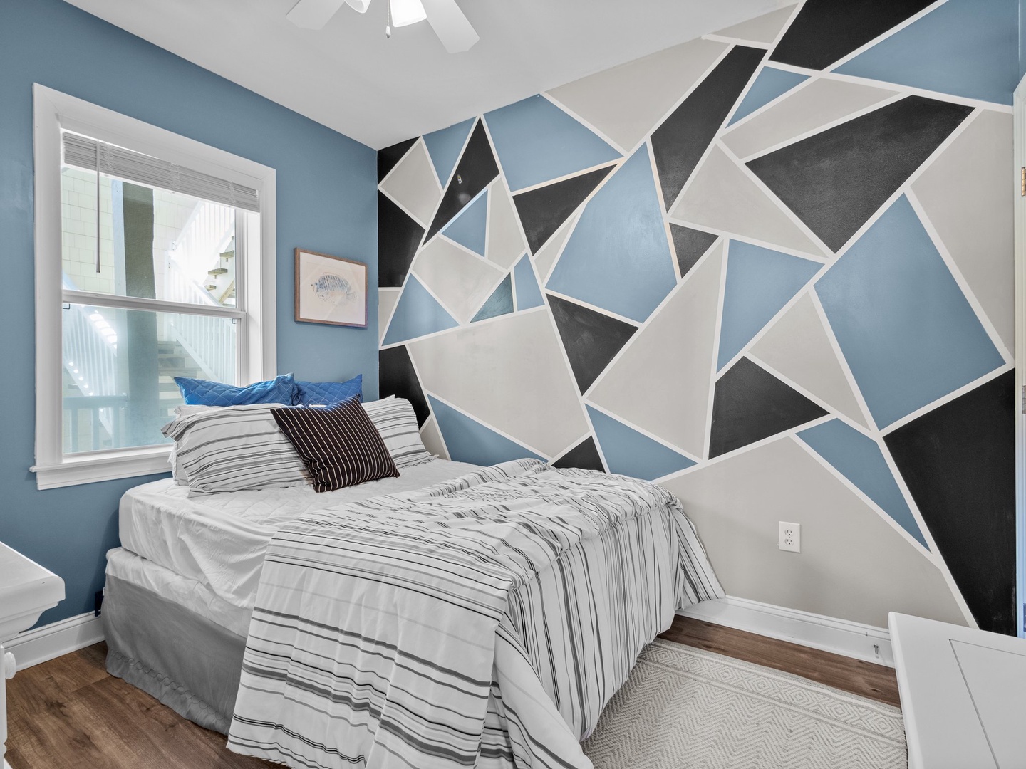 Drift off to sleep surrounded by this striking geometric accent wall, where bold blues and grays create a modern artistic backdrop for your restful nights.