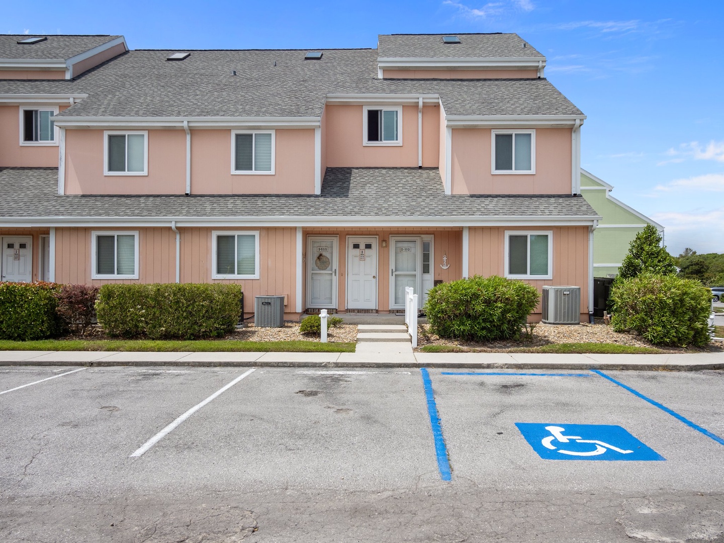Property building with convenient parking and accessible spaces, featuring charming pink townhouse-style accommodations in a peaceful residential setting.