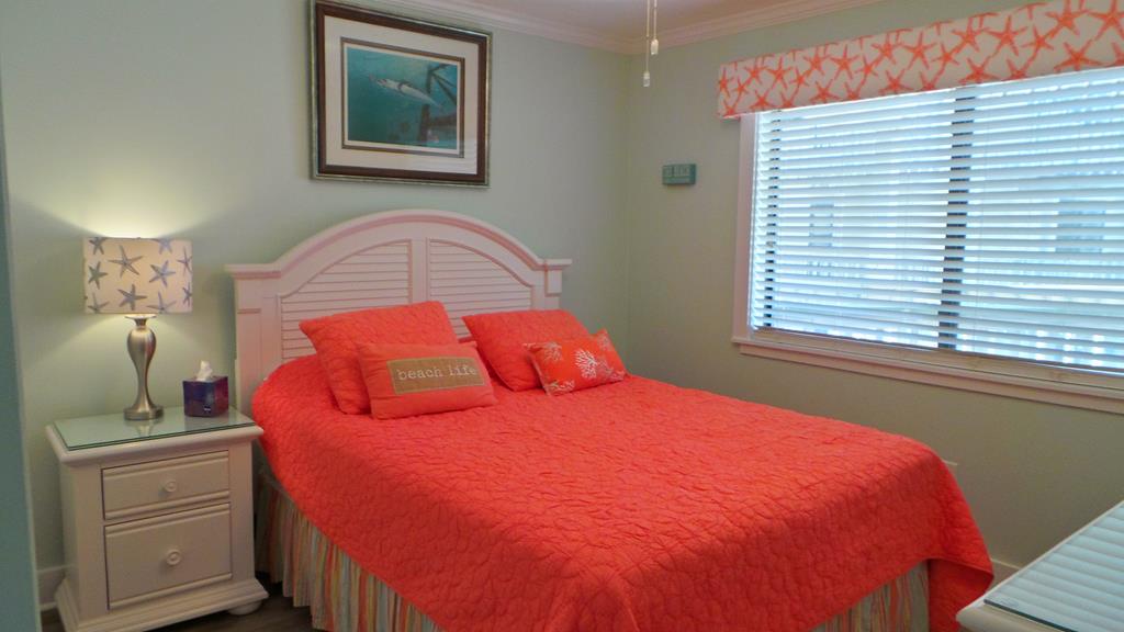 Drift off in this bright coastal bedroom featuring coral bedding, starfish decor, and natural light streaming through your window.