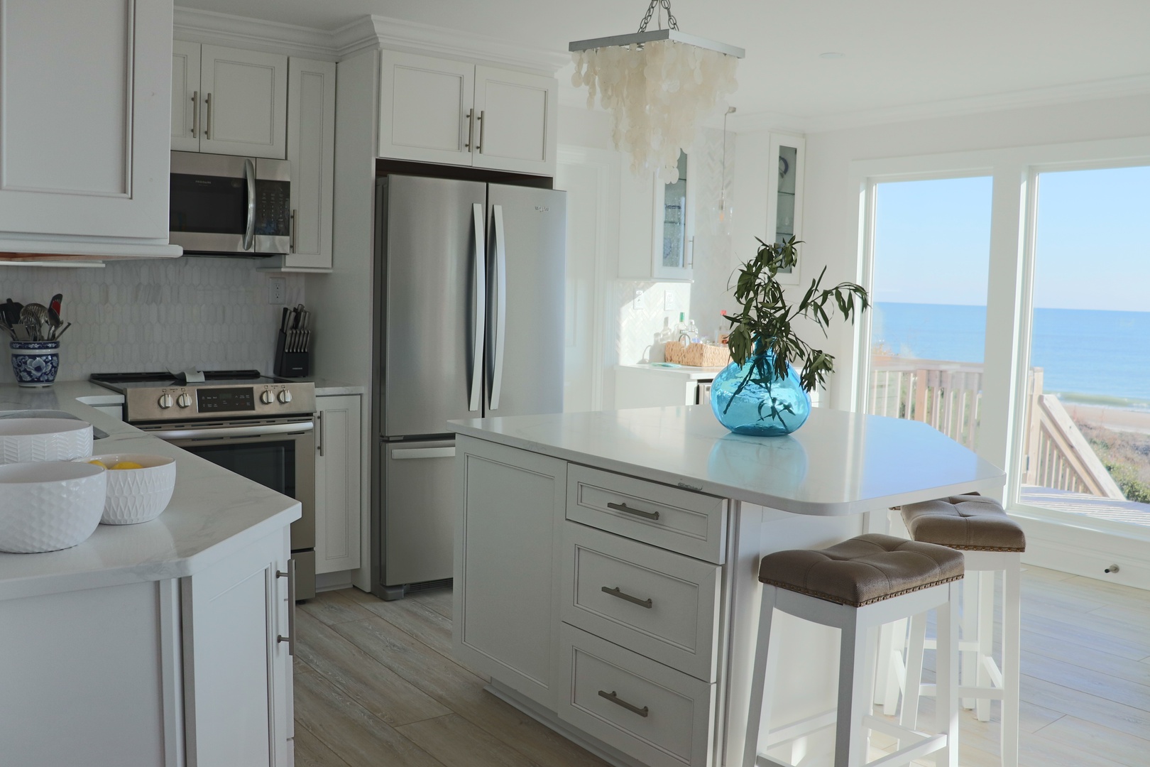 Your bright, coastal kitchen features modern appliances and stunning ocean views through floor-to-ceiling windows.