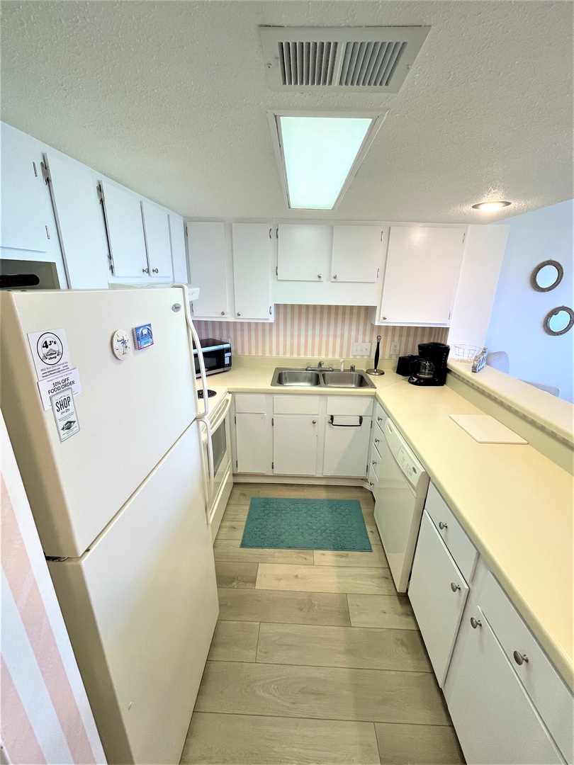 Your fully-equipped kitchen features crisp white cabinets, modern appliances, and ample counter space for preparing meals during your stay.