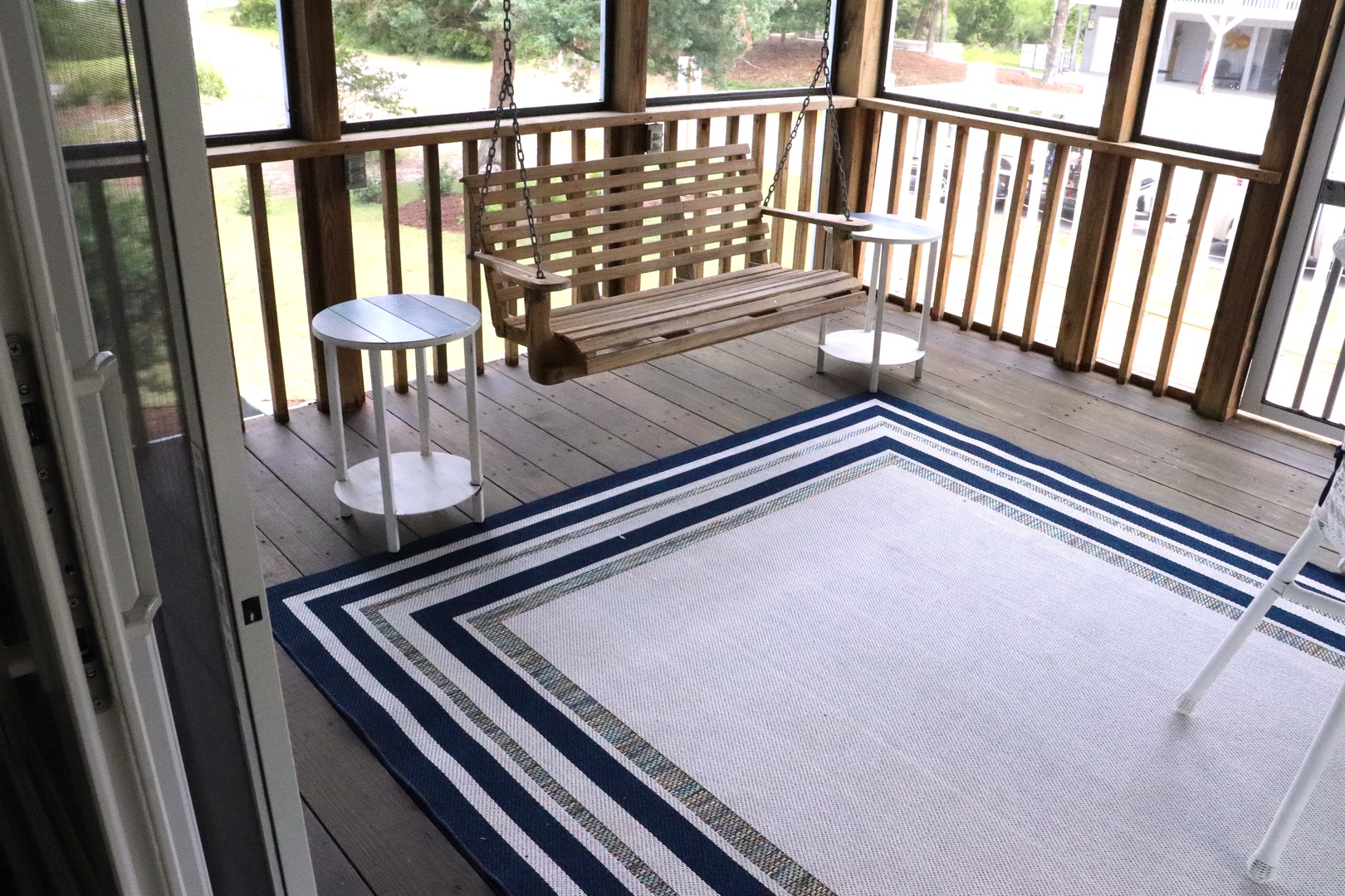 Your screened porch offers peaceful moments with a charming swing and side tables overlooking neighborhood views.