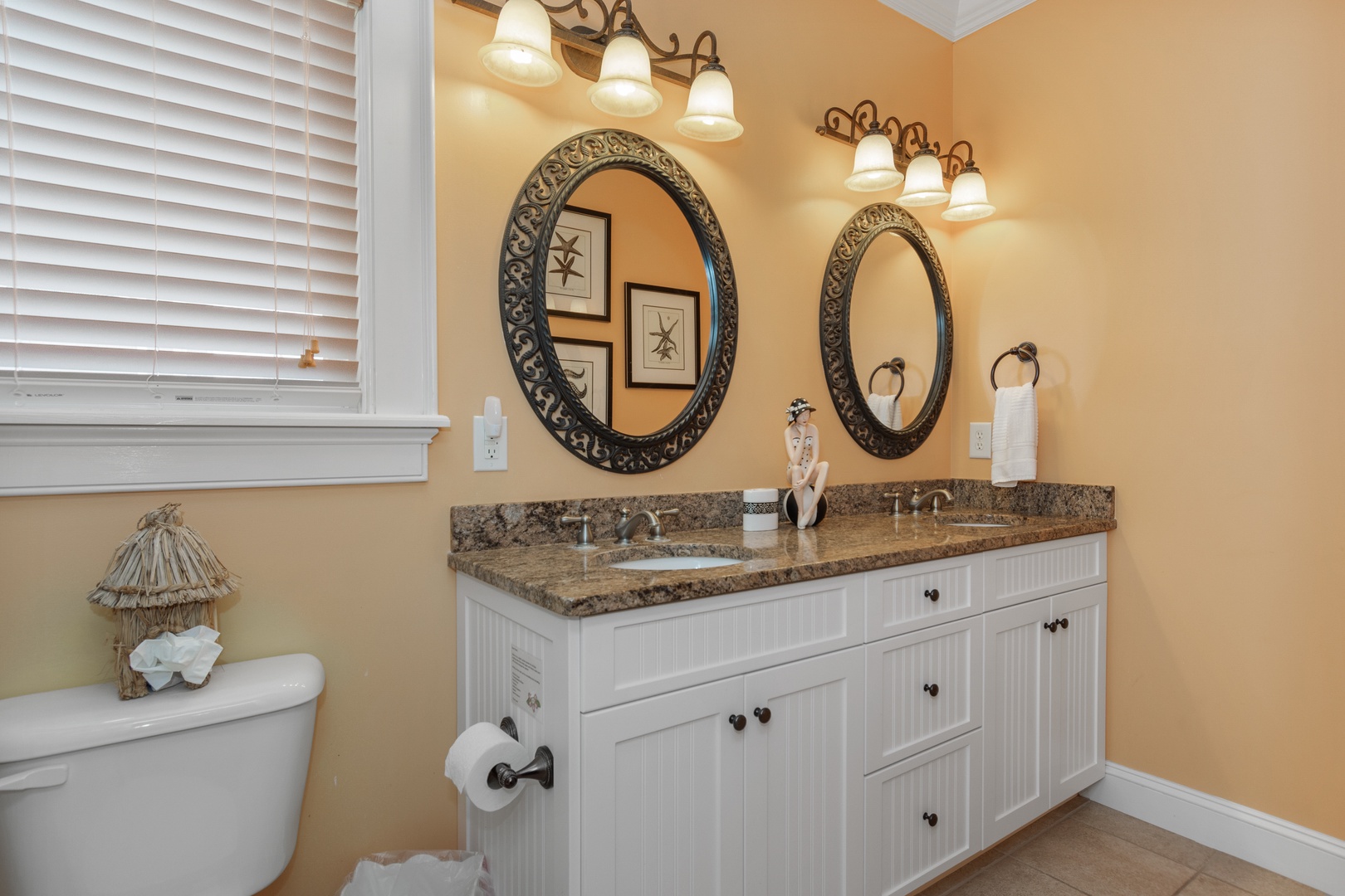 Your elegant dual-sink bathroom features granite countertops, ornate mirrors, and warm lighting for your morning routine.