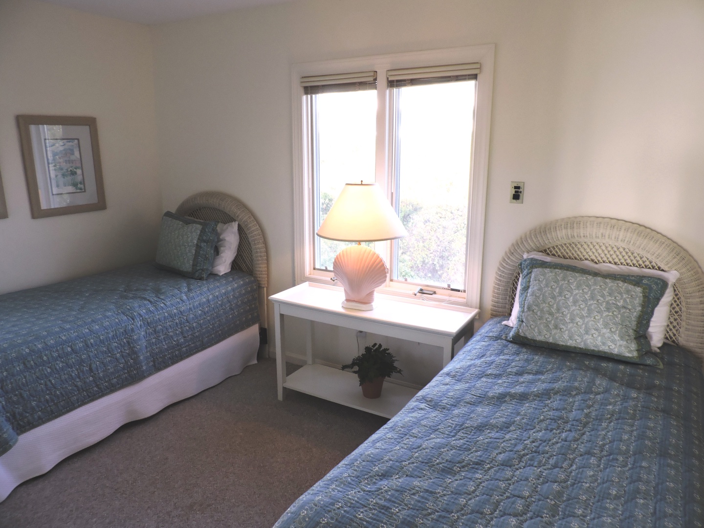 Wake up to natural light streaming through your bedroom windows, where twin beds with coastal blue linens offer peaceful rest.