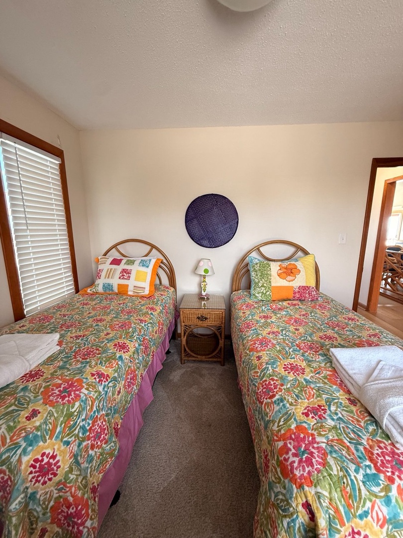 Wake up in this cheerful twin bedroom, where vibrant floral bedding and coastal rattan accents invite you to start your day feeling refreshed and ready for adventure.