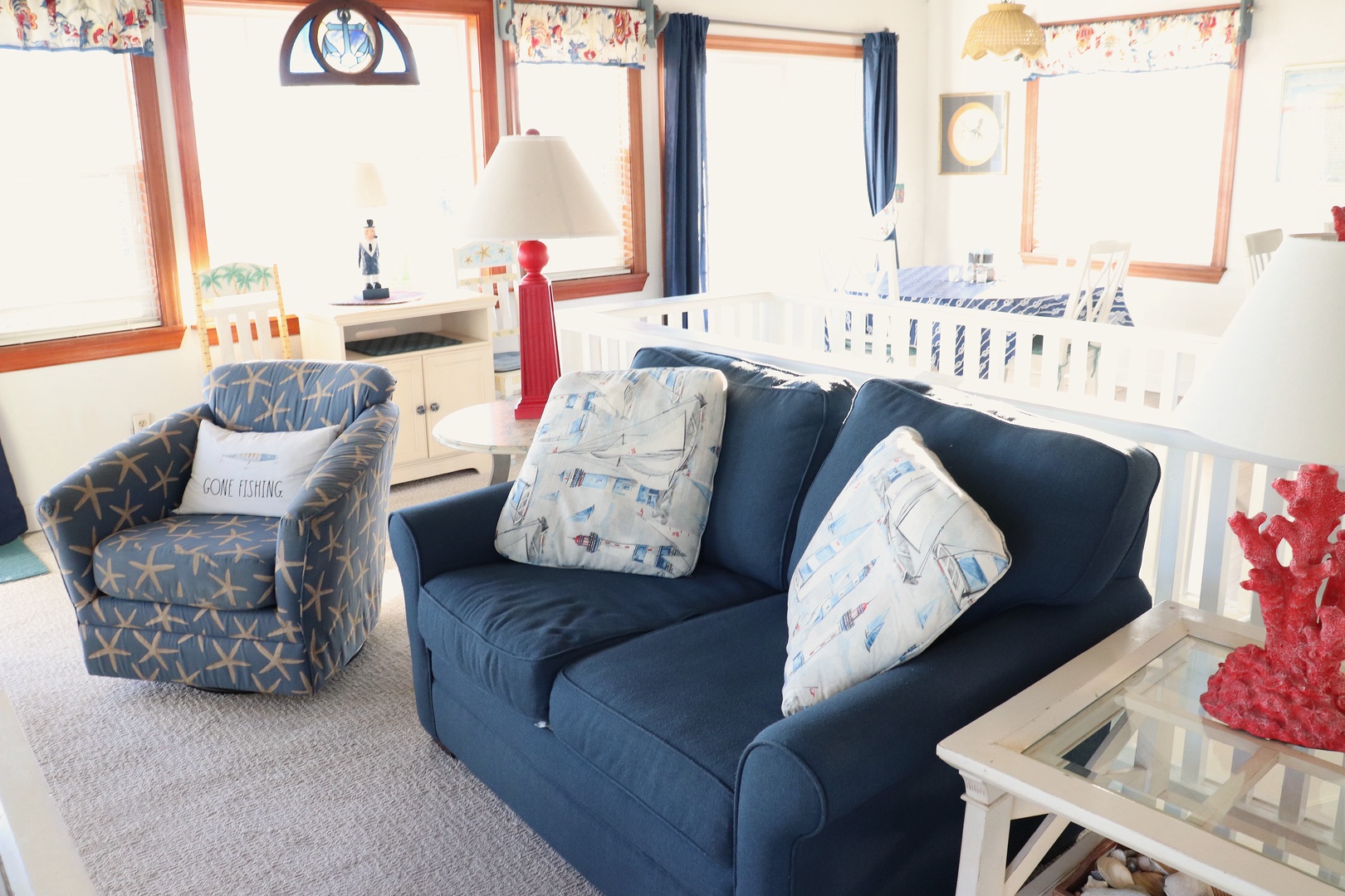 Your nautical-themed living room welcomes you with cozy navy seating and charming maritime touches throughout this bright, airy space.