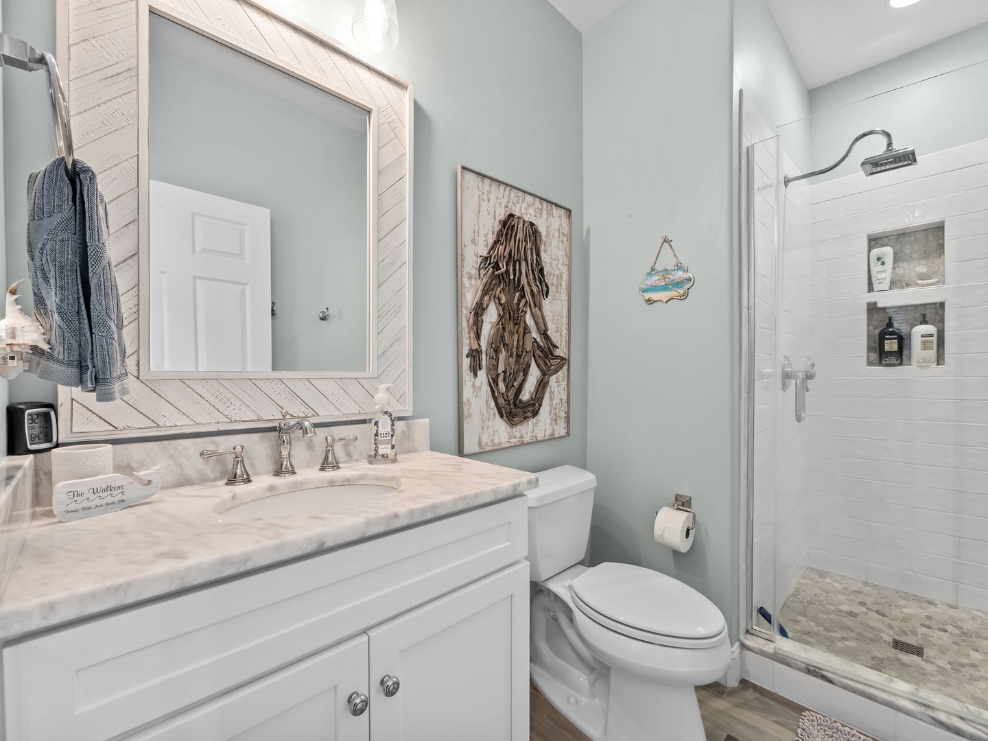 Refresh in your coastal-themed bathroom with marble countertops, rainfall shower, and charming mermaid artwork that sets a beachy mood.