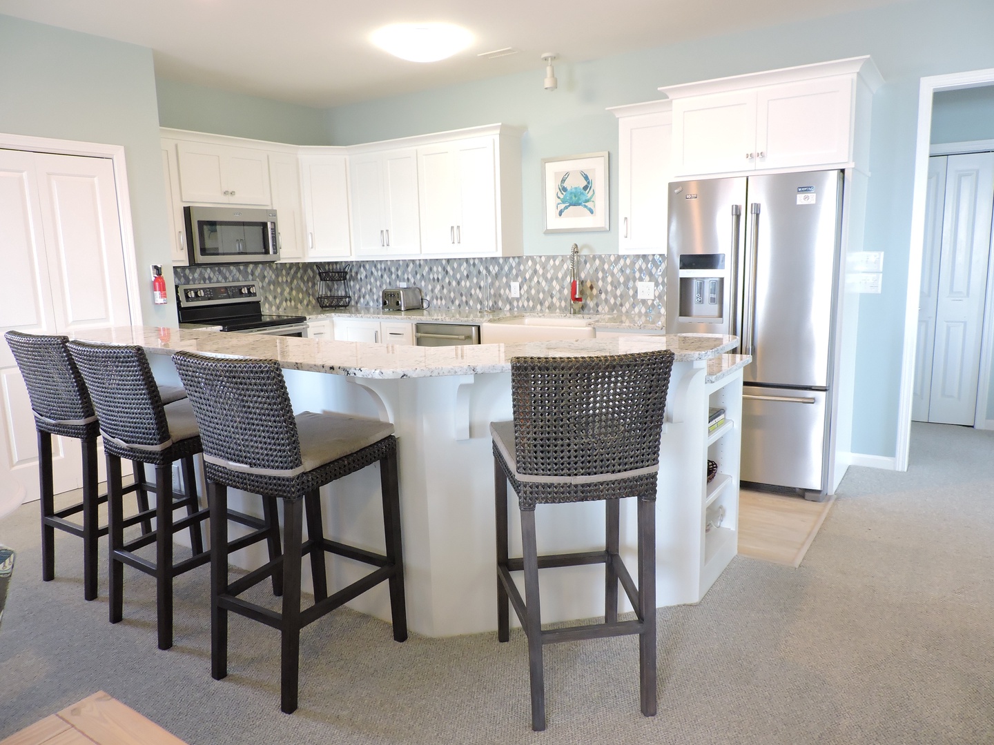 Your fully-equipped kitchen features modern appliances, granite counters, and coastal-themed decor perfect for preparing vacation meals together.