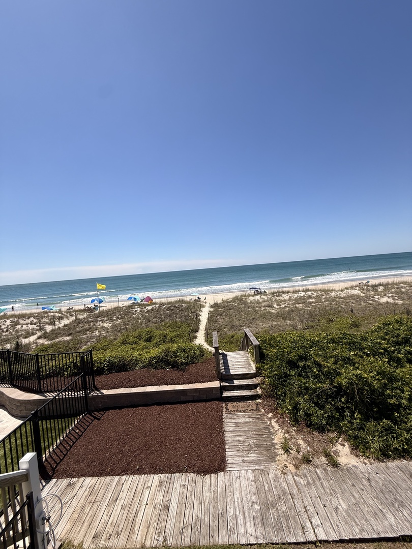 A tranquil beachfront property with direct access to pristine shores, natural coastal surroundings, and a private walkway leading to the waterfront.
