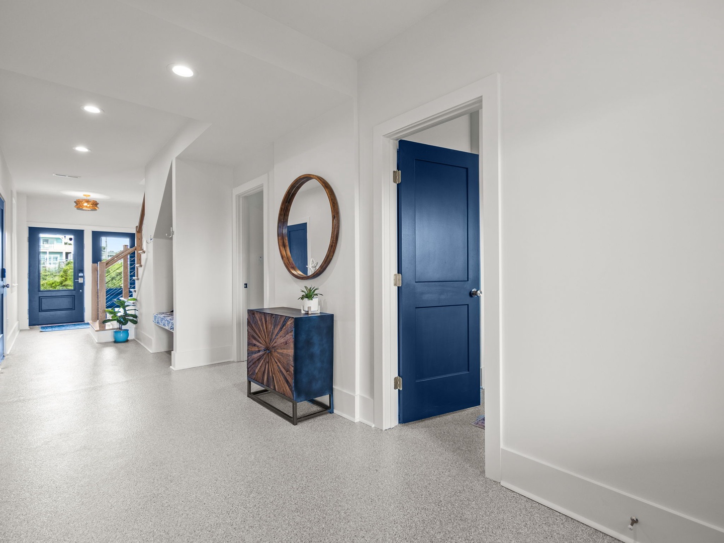 Step into your stylish hallway featuring polished terrazzo floors, bold navy doors, and warm wood accents that create an inviting first impression.