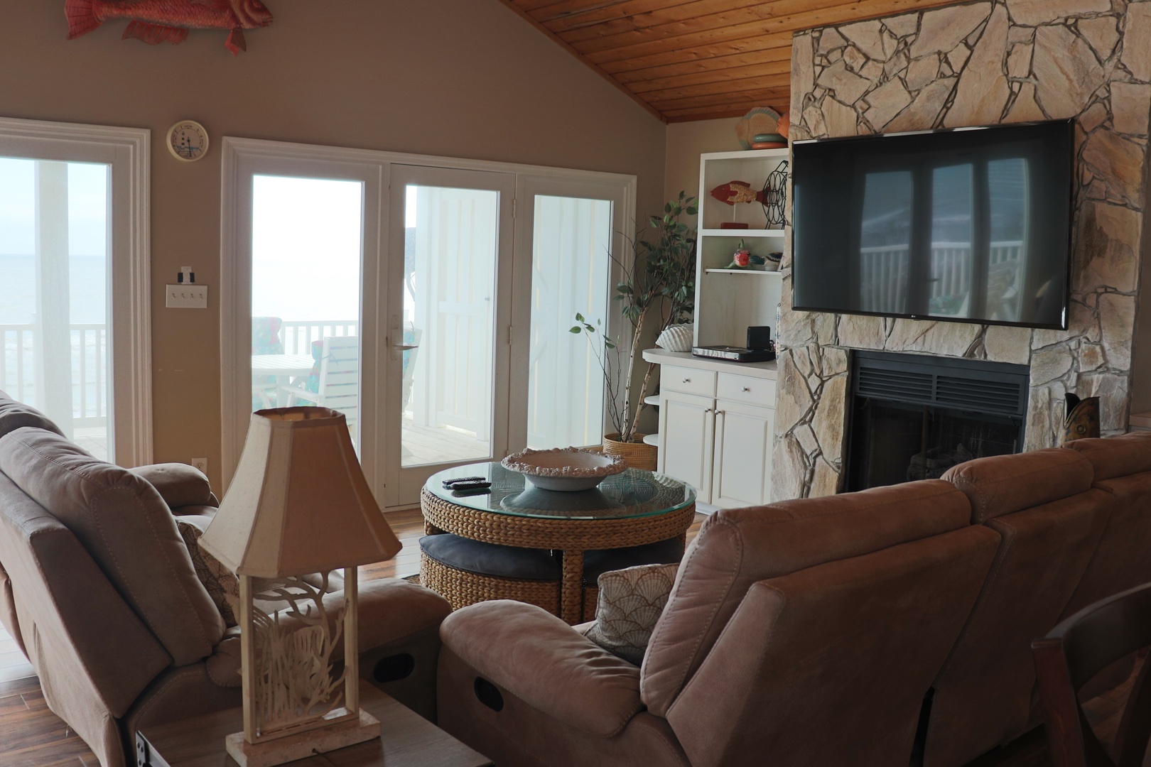 Sink into plush recliners by your stone fireplace, where warm wood ceilings and natural light create the perfect retreat for cozy evenings together.