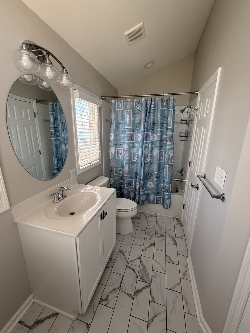 Freshen up in this bright, modern bathroom with a walk-in shower, elegant marble-look tile, and thoughtful fixtures designed for your comfort.