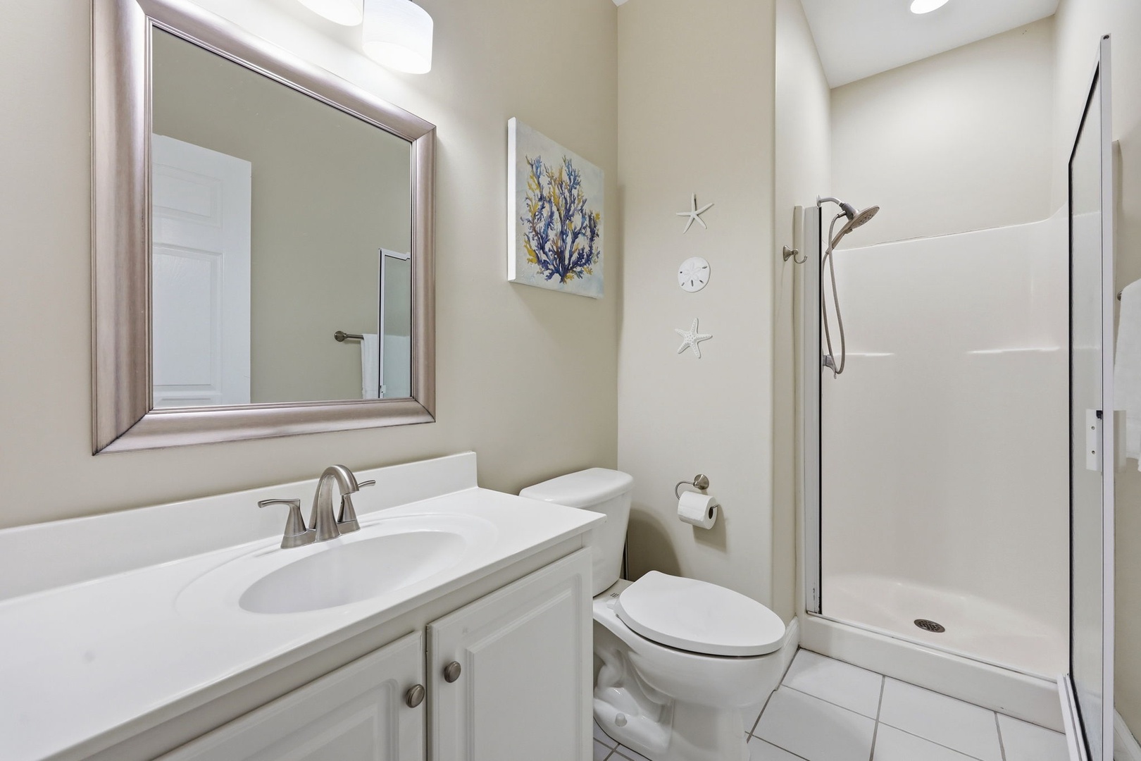 Your private bathroom features coastal charm with soft, neutral tones and a clean walk-in shower—perfect for refreshing after a beach day or exploring nearby attractions.