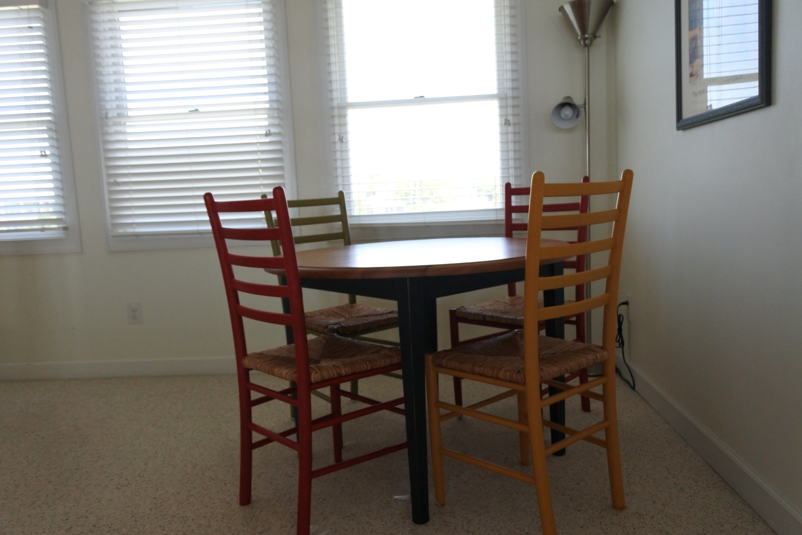 Enjoy meals at your cozy dining table with colorful chairs and natural light streaming through bright windows.