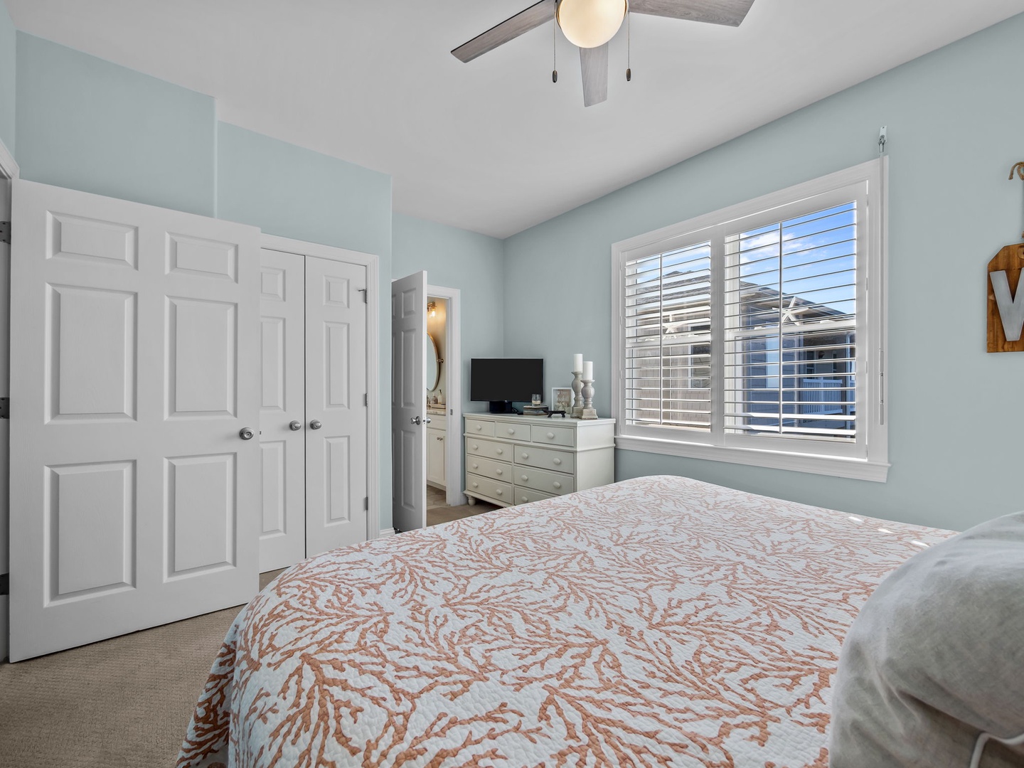 Rest peacefully in your serene bedroom with soft mint walls, elegant furnishings, and abundant natural light from plantation shutters.