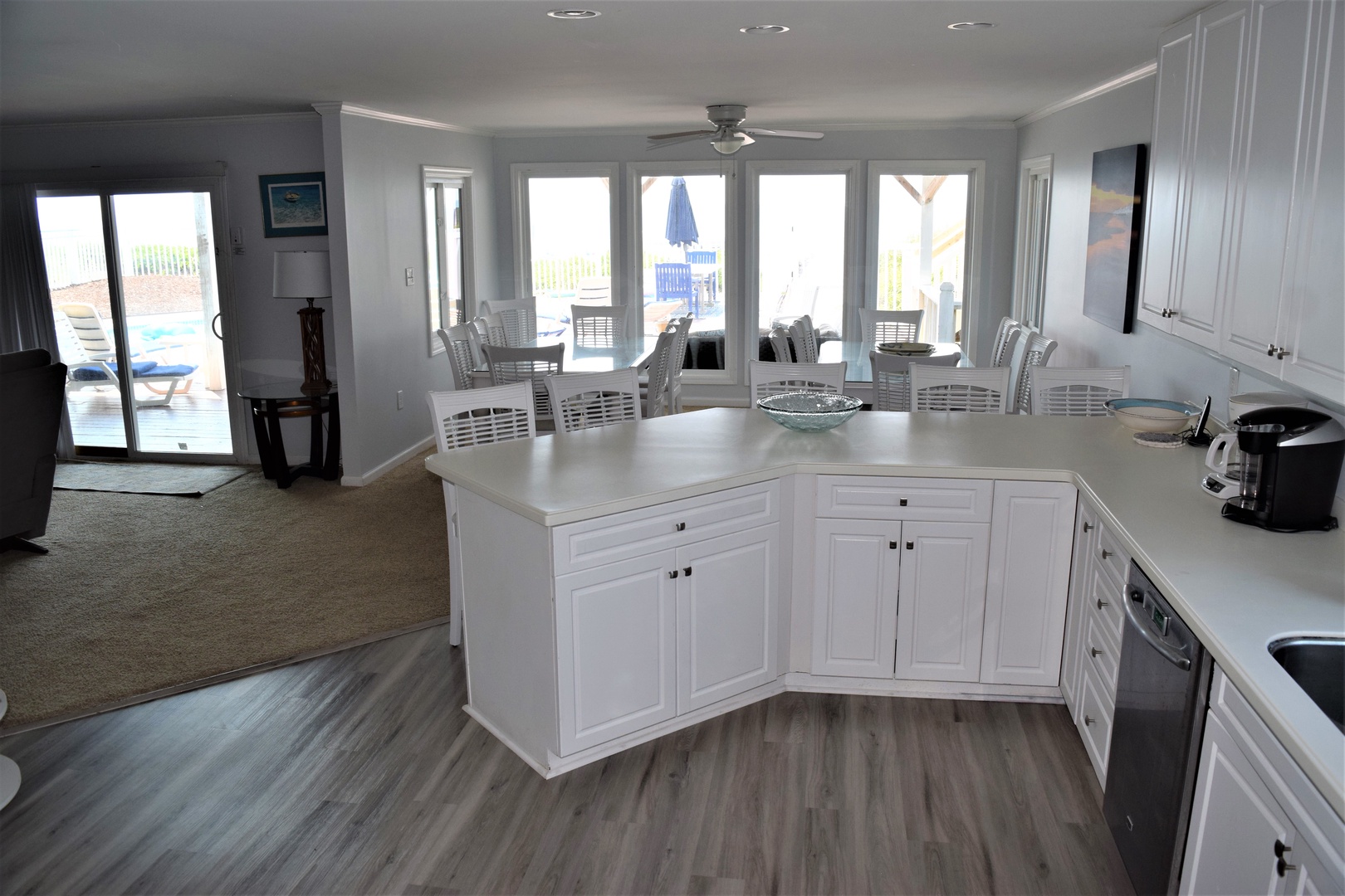 Your bright kitchen island opens to a dining area with pool views through expansive windows.