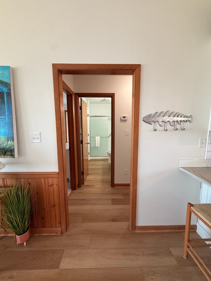 Your home away from home features warm wood accents and thoughtful coastal touches, like the playful fish-shaped hooks welcoming you as you move between spaces. Through the doorway, natural light streams in, inviting you to settle in and relax.