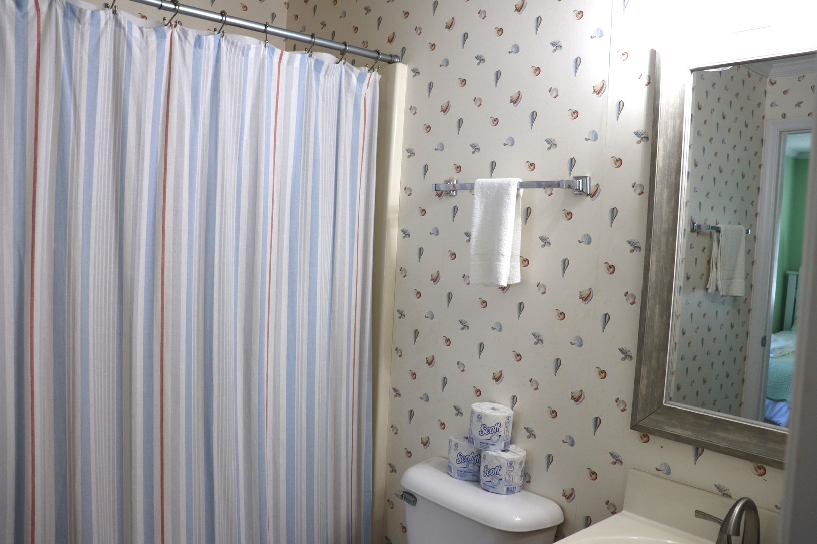 Your charming bathroom features whimsical seashell wallpaper and fresh towels, creating a coastal retreat for your morning routine.